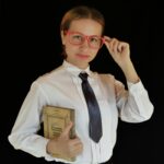Confident businesswoman with glasses holding book, studio shot.